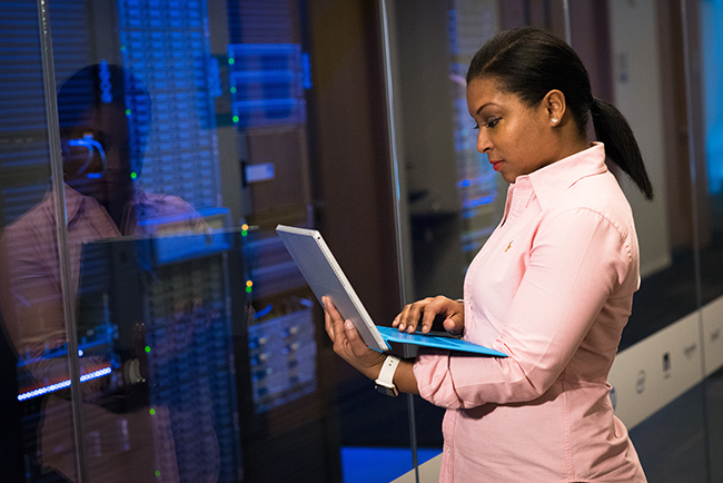 African American technologist working in a server room.